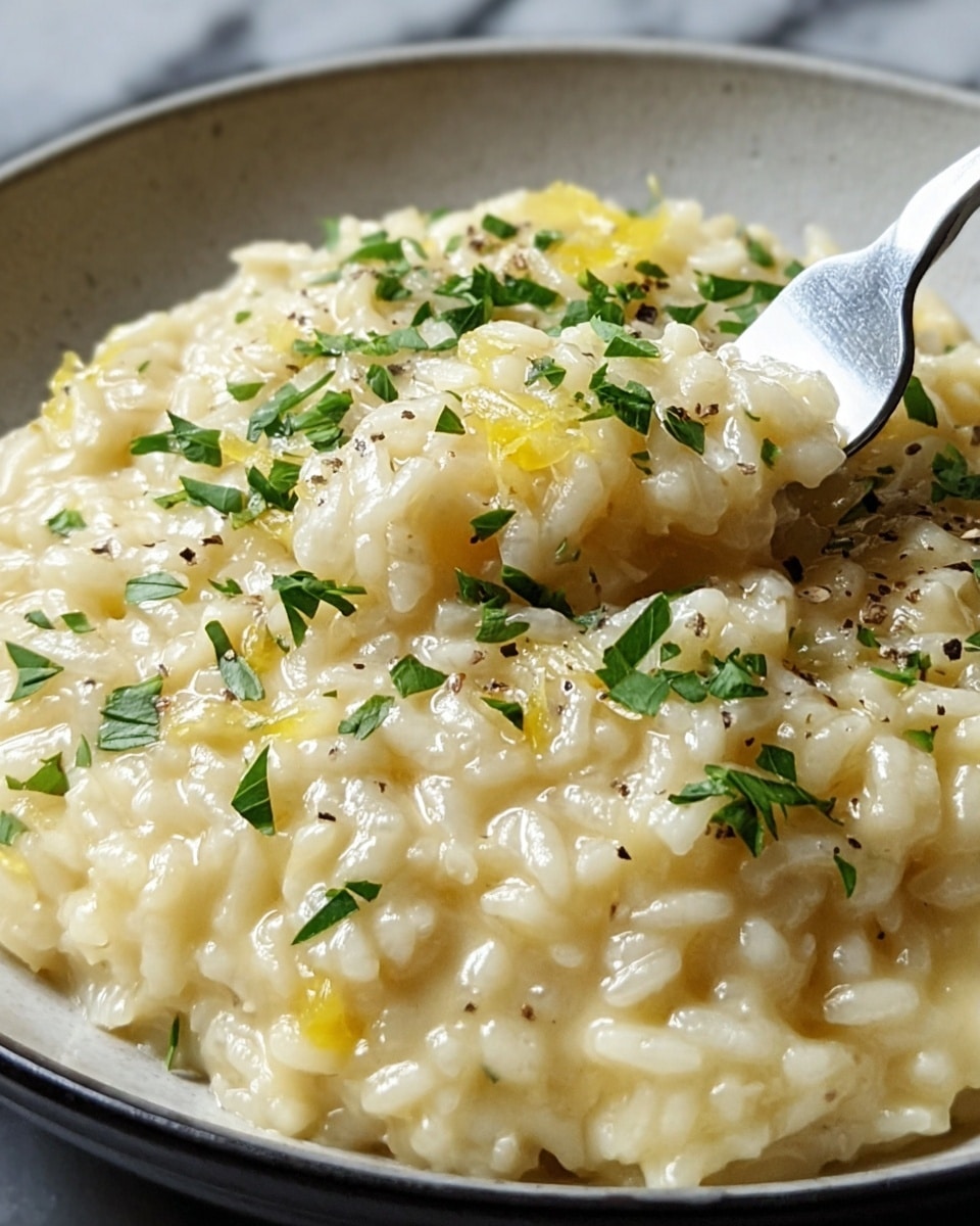 A close-up view of creamy risotto served in a white bowl, showing a thick, slightly shiny texture of cooked rice mixed with small pale yellow pieces, likely cheese, and sprinkled with fresh green chopped herbs on top. A silver fork is lifting a spoonful of the risotto from the bowl. The image background shows a white marbled texture. Photo taken with an iphone --ar 4:5 --v 7