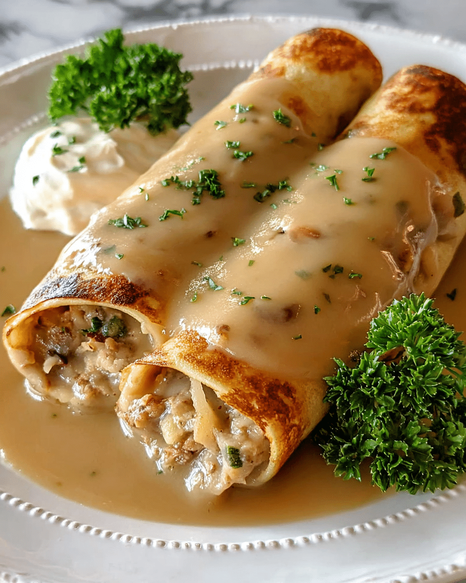 Two rolled crepes filled with a chunky mixture of light brown and beige ingredients, showing bits of green herbs and small pieces of vegetables inside. They are covered with a thick, smooth, light brown gravy that glistens on the surface. The crepes sit on a white plate with a detailed edge. On the side, there is a dollop of creamy white sauce and some fresh curly green parsley for garnish. The background is a white marbled texture. photo taken with an iphone --ar 4:5 --v 7
