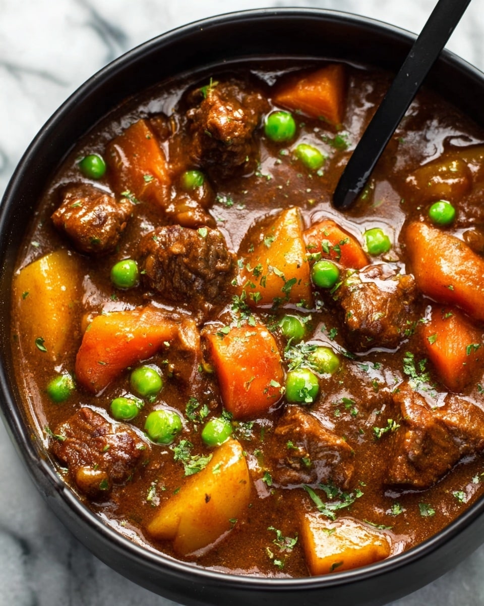 A close-up view of a black bowl filled with rich brown beef stew, showcasing chunks of tender brown meat mixed with bright orange carrot slices, yellowish potato pieces, and scattered bright green peas. The stew has a thick, glossy texture with visible small green herb bits sprinkled throughout. A black spoon rests inside the bowl, partially submerged in the stew. The bowl is placed on a white marbled surface. photo taken with an iphone --ar 4:5 --v 7
