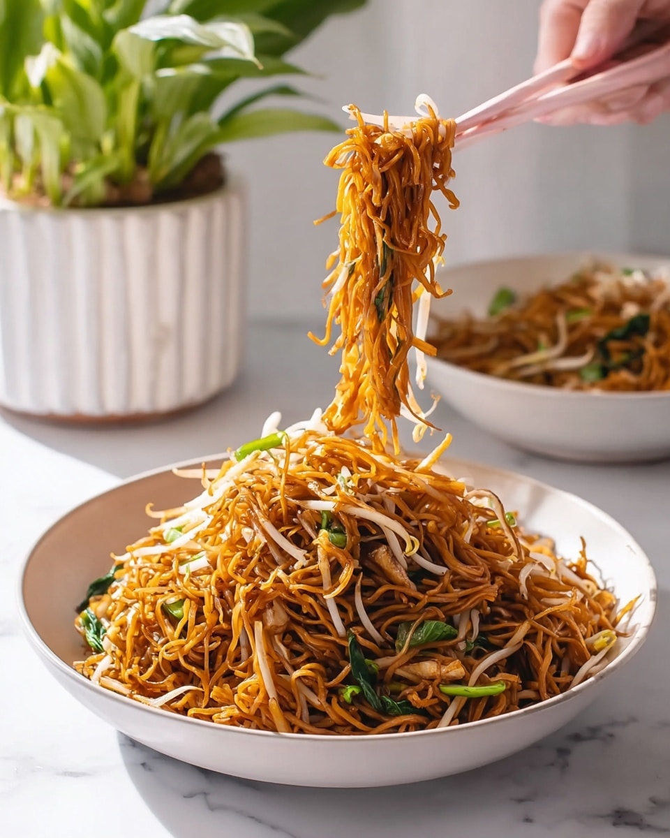 A white bowl filled with two layers of thin, brown fried noodles mixed with white bean sprouts and scattered green vegetable pieces. The top layer shows noodles being lifted by a woman's hand holding light pink chopsticks. Behind the main bowl, there is another white bowl with the same noodles, slightly blurred, and a green plant in a white square pot on a white marbled surface with a pink and white checkered cloth in the front. photo taken with an iphone --ar 4:5 --v 7