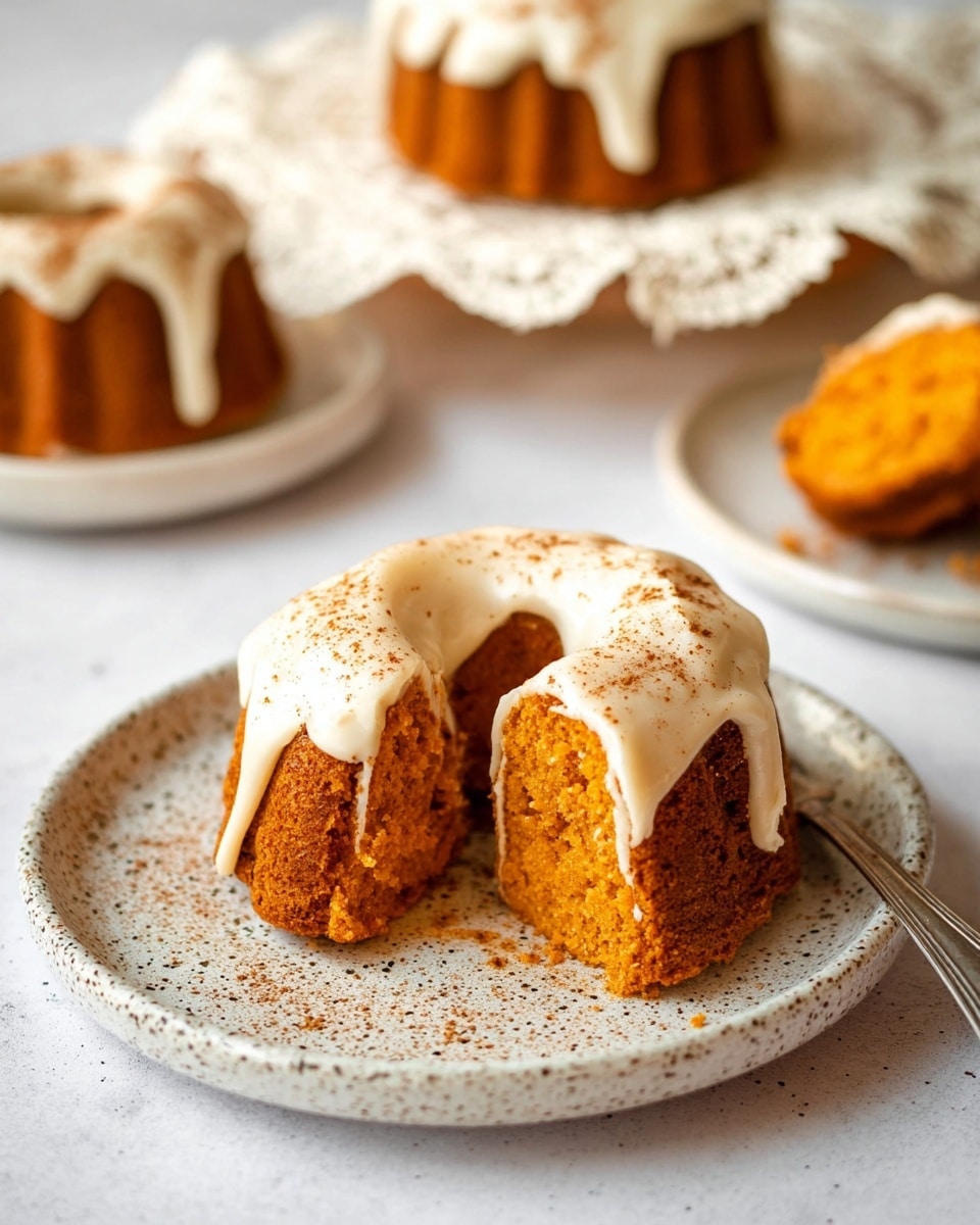 The image shows five small bundt cakes arranged on a round white plate with a dotted rim. Each bundt cake is golden brown and topped with a thick layer of white icing that drips slightly down the sides. There is a light dusting of brown cinnamon powder sprinkled over the icing and the plate. The plate sits on a piece of brown burlap, all placed on a white marbled surface. The bottom right corner shows part of a silver fork handle. Photo taken with an iphone --ar 4:5 --v 7