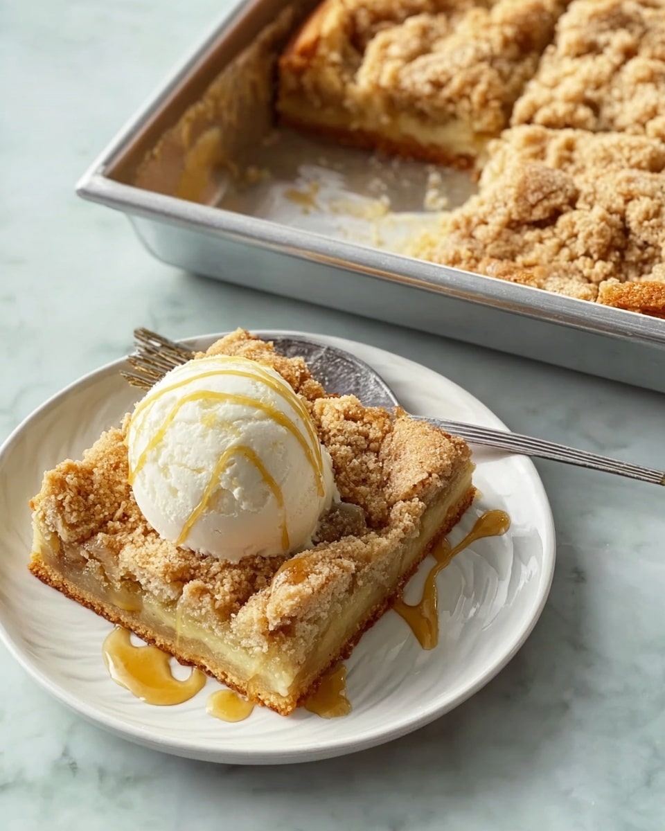 A slice of crumb cake with a thick golden-brown crust forming the bottom and edges, topped with a dense, crumbly streusel layer that is light tan and textured with chunks; the cake slice sits on a white square plate with rounded edges, next to a scoop of white vanilla ice cream drizzled with thin caramel sauce lines that also extend onto the plate. Next to the plate is a metal baking tray holding the remaining crumb cake, showing the same golden crust and crumbly streusel top, with one piece cut out. The scene is set on a white marbled textured surface. photo taken with an iphone --ar 4:5 --v 7