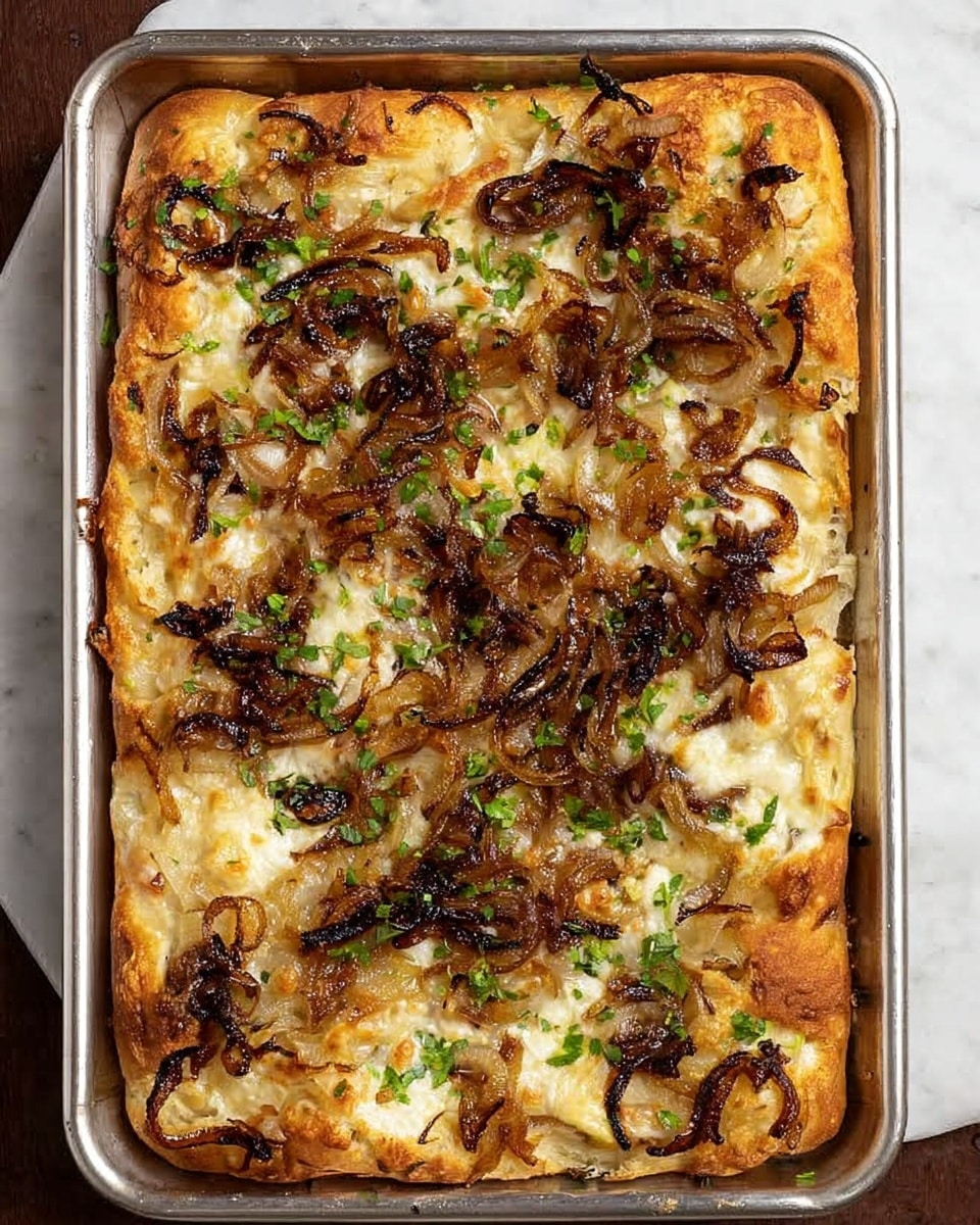 A rectangular pizza in a silver baking tray over a white marbled surface, topped with a golden-brown crust layer that looks soft and airy. The first layer of melted cheese is creamy white with some golden spots. On top, there is a scattering of caramelized onions that range from deep dark brown to light golden, adding a textured and uneven layer. Small green herb bits are lightly sprinkled all over, giving fresh color contrast. The cheese melts through the onion pieces, creating a slightly shiny surface. photo taken with an iphone --ar 4:5 --v 7