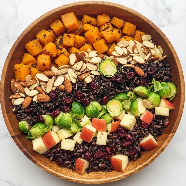 A wooden bowl filled with a colorful mixed dish on a white marbled surface. The dish has several layers including dark wild rice, bright orange cubes of roasted squash, light beige slices of almonds, green pieces of chopped Brussels sprouts, small red dried cranberries, and bits of apple with red skin and white flesh. The textures vary from soft roasted vegetables to crunchy nuts and tender grains, all mixed together in a rustic, hearty presentation. Photo taken with an iphone --ar 4:5 --v 7