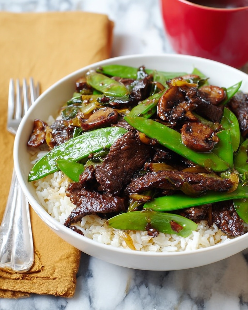 A bowl filled with a mix of cooked beef strips, green snow peas, and sliced mushrooms. The beef pieces are dark brown with a slightly shiny surface, scattered throughout the bowl. The bright green snow peas add a fresh look, with their smooth and glossy skin contrasting with the darker tones around them. The mushrooms are light brown with a soft texture, mixed evenly among the beef and peas. The bowl is white and sits on a white marbled surface. A fork is placed next to the bowl on the surface. Photo taken with an iphone --ar 4:5 --v 7