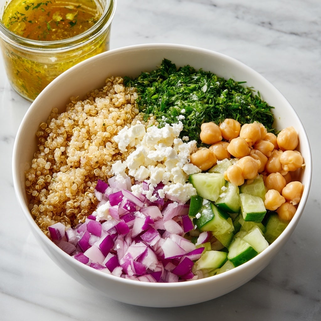 A close-up view of a white bowl filled with a colorful quinoa salad made of three main layers: the base layer of light beige quinoa grains, scattered with diced green cucumber chunks and small pieces of purple onion, mixed with light beige chickpeas and green herbs. On top, a golden brown dressing is being poured from a small clear mason jar by a woman's hand with pink painted nails. Two wooden salad spoons rest inside the bowl, partly submerged in the salad. The setting includes a white marbled textured surface beneath the bowl. photo taken with an iphone --ar 4:5 --v 7