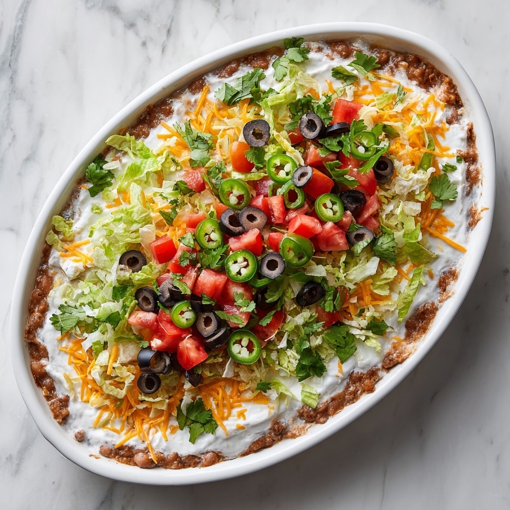 The dish is a layered taco salad served in a white bowl placed on a white marbled surface. The base layer consists of cooked ground beef, dark brown and crumbly, mixed with small pieces of red bell pepper. Above this is a layer of shredded lettuce, light green and fresh. This is topped with sliced black olives, round with a smooth texture, and grated cheese in white and yellow strands. Dollops of creamy white sour cream are spread over the top. Small pieces of diced red tomato and fresh green cilantro leaves add extra color and freshness throughout the layers. A fork is lifting a portion of the salad, showing the mix of these layers together. Photo taken with an iphone --ar 4:5 --v 7